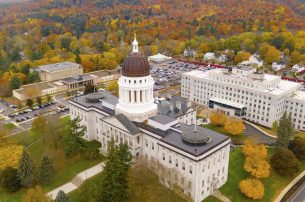 Picture of the capitol building in Augusta, Maine, surrounded by yellow and orange fall foliage.
